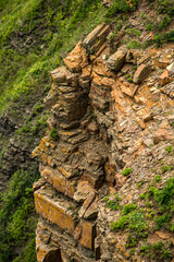 A steep cliff that is covered with numerous rocks and patches of grass on it