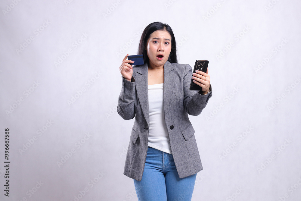 Wall mural beautiful adult office girl asia shocked to camera holding cellphone smartphone and holding credit d