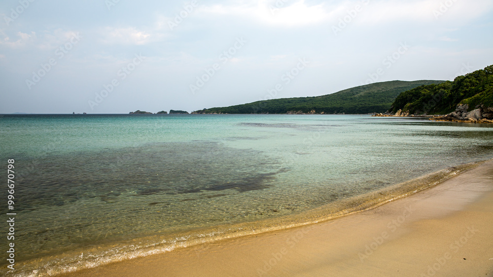 Wall mural a large body of water with a sandy beach in the foreground