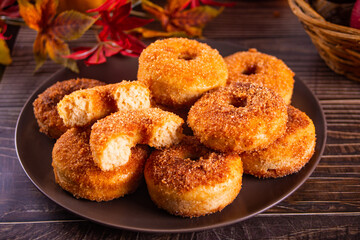 Sweet homemade apple cider donuts with cinnamon sugar on the wooden table. Autumn food.