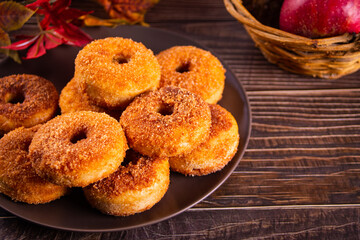 Sweet homemade apple cider donuts with cinnamon sugar on the wooden table. Autumn food.