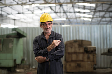 Portrait of senior male engineer standing in factory. Senior male technician wear safety uniform, helmet in industry factory