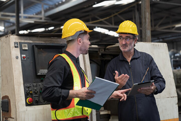 Two male engineer checking, repair, maintenance CNC machine in factory. Group of male technician working with CNC machine during manufacturing process