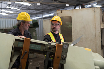 Two male engineer checking, repair, maintenance CNC machine in factory. Group of male technician working with CNC machine during manufacturing process