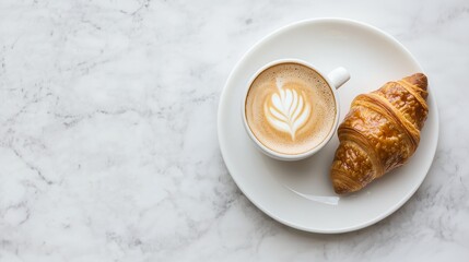 A warm cup of coffee paired with a flaky croissant on a marble surface, perfect for a cozy breakfast or brunch setting.