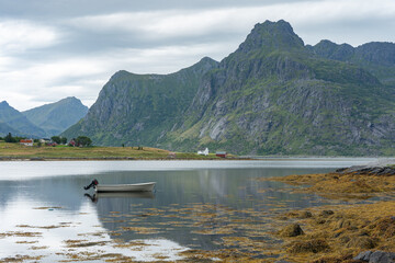 Swampy moss lake with power boat and houses and mountains in the background, Lofoten Norway