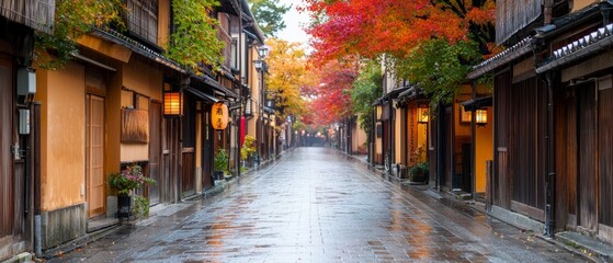 Fototapeta premium A wet street dotted with wooden structures; buildings sport orange and red foliage atop, beneath