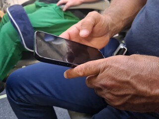 A passenger holds a smartphone while seated on an airplane during a flight