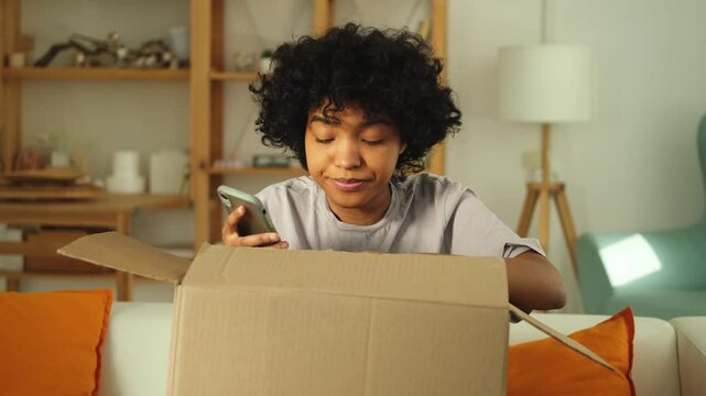 Unhappy african woman unpack delivered box receiving damaged shipping problem in postal service. Annoyed confused customer receiving wrong parcel talks to customers support. Bad delivery services