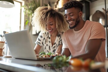 A diverse couple cooking dinner together, with a laptop open on the counter