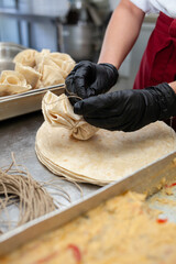 Close shot for preparing filo pastry pouches in restaurant kitchen, no face