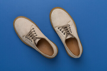 Beige suede shoes on color background, top view