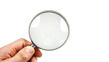 A hand holds a magnifying glass over an abstract background of colorful vertical lines.