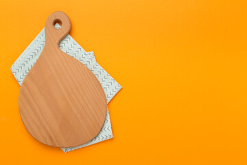 Cutting board with napkin on color background, top view
