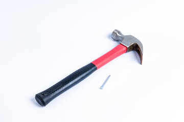 Close up a nail and medium sized hammer that has two functions as a nail pick and nail hammer, with a handle covered in black and red rubber isolated on a white background. Little bit rusty