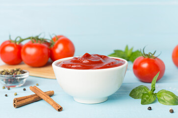 Delicious ketchup with spices and tomatoes on wooden table