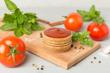 Delicious ketchup with spices and tomatoes on wooden table