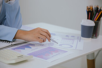An Asian businesswoman works at her desk in an office. She works hard on her laptop, communicates online, manages her tasks, and easily balances her career.