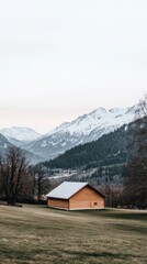 The majestic Mountains rise in the background beside an old barn and rustic fence against a bright blue sky