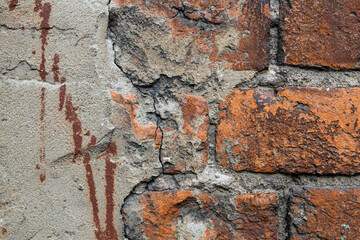 A weathered brick wall showcases peeling plaster and cracks, revealing unique textures and urban stories.