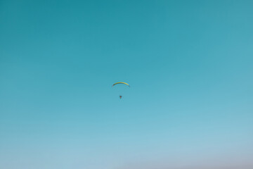 Alone paraglider flying in the blue sky against the background of clouds. Paragliding in the sky on a sunny day. High quality 