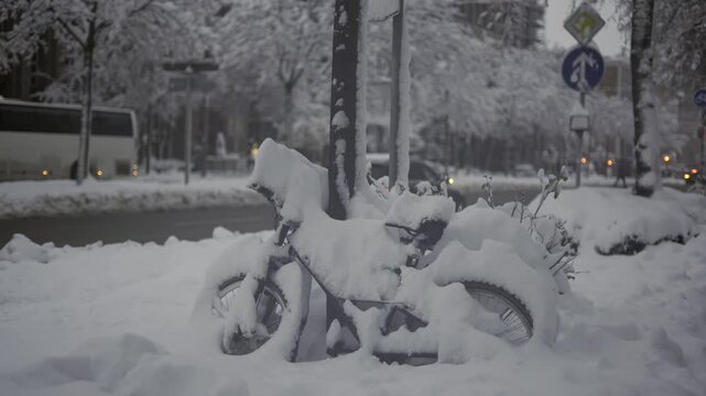 Munich, Germany. Snowfall in Muenchen. Snow covered bicycles in city parking lot. Snow drifts and bikes in snow in a parking area. Schneeeinbruch in Munchen, Deutschland. 