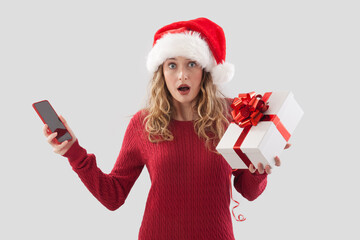 Amazed Santa Claus woman with cellphone and Merry Christmas gift box package with red bow. For offer sale promotion, shopping online, advertising banners, posters or gift cards, isolated background
