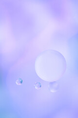 Macro drops of oil on the surface of the water. Delicate blurred cosmetic background. Vertical photo