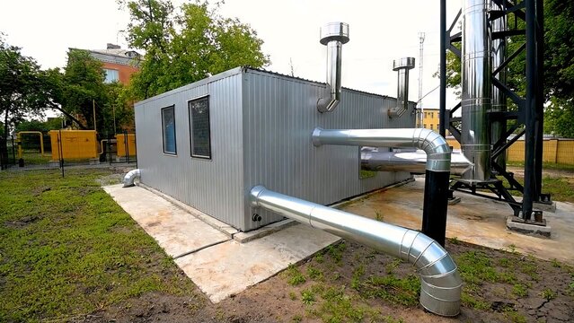 The building of a small autonomous modular boiler house for heating and water heating in the city. A small modular house produces shiny pipes for water and ventilation. The concept of decentralization