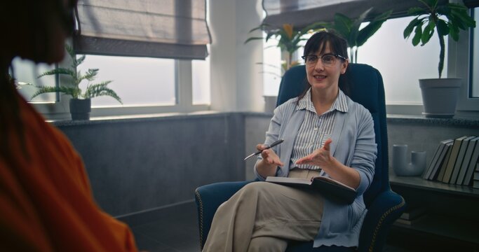 Beginning of psychotherapy: female psychotherapist starts therapy with African American teenager. Therapist talks to teen boy, asks questions to find out problems. Psychology and psychotherapy.