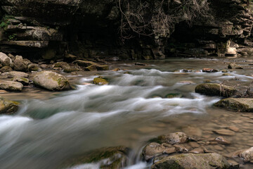This image captures a fast-flowing river rushing over a rocky bed, creating whitewater rapids. The power of the water contrasts with the immovable rocks.
