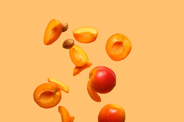 Flying fresh apricots with pieces on orange background