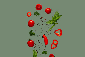 Flying peppercorns, vegetables and herbs on green background