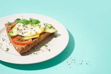 Plate of tasty sandwich with egg on blue background