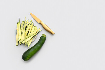 Plate with slices of fresh green zucchini on white background