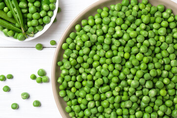 Fresh green peas and pods on white wooden table, flat lay