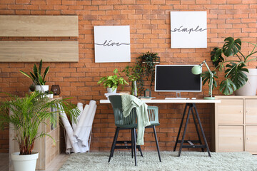 Interior of stylish office with modern workplace, shelving unit and houseplants