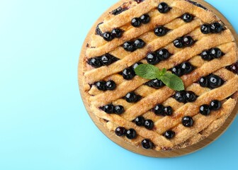Delicious homemade blueberry pie with mint on light blue background, top view. Space for text