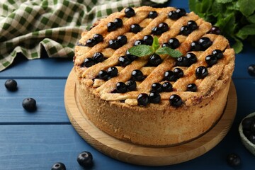 Delicious homemade blueberry pie with mint and fresh berries on blue wooden table, closeup