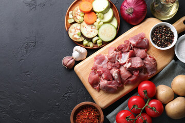 Cooking stew. Uncooked meat and vegetables on black table, flat lay. Space for text