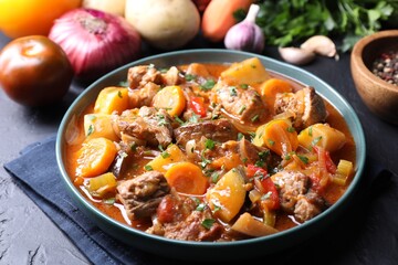 Delicious stew and different ingredients on black table, closeup