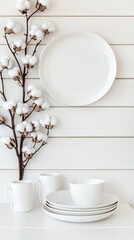 A beautifully arranged modern table setting features white ceramic plates and cups accompanied by cotton flowers, creating a serene and inviting aesthetic for creative designs