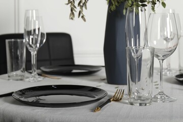 Stylish table setting with black dishware in dining room