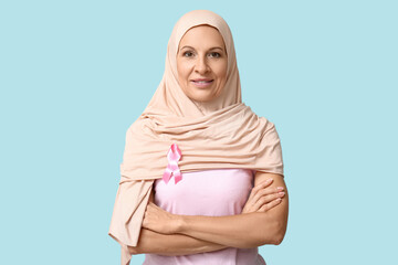 Muslim mature woman with pink ribbon on blue background. Breast cancer awareness concept