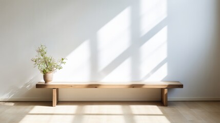 A minimalist wooden bench sits against a white wall, bathed in natural light, with a potted plant adding a touch of simplicity and elegance.