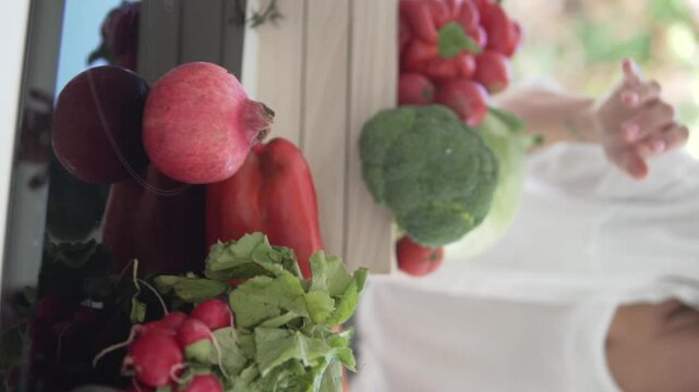Vertical video. Woman collecting a basket of farm vegetables, close-up of a box with a woman's hands