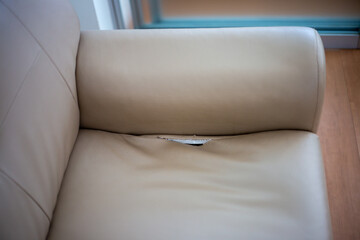 A leatherette sofa with a torn seam. An old sofa in an apartment
