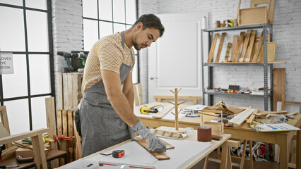 A young hispanic man with a beard works diligently in a well-equipped carpentry workshop, representing craftsmanship and skill.