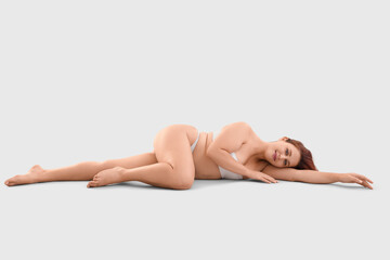 Fototapeta premium Beautiful plus size woman in underwear lying on light background