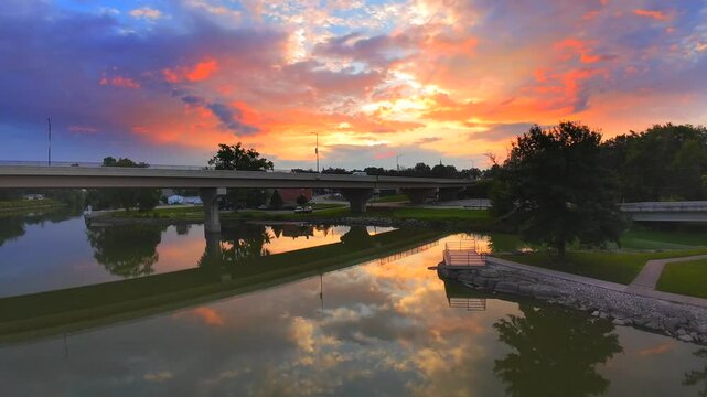 FPV drone flight over tranquil river reflecting dramatic sunrise sky.
